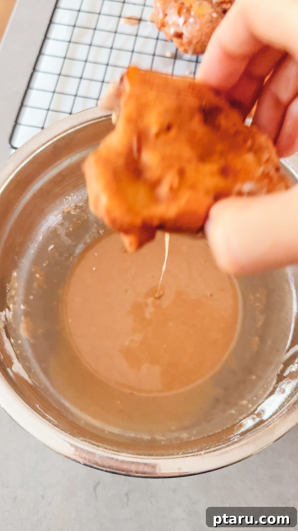 Crispy Homemade Apple Fritters with Cinnamon Glaze 9 Dipping a warm apple fritter into the glaze.