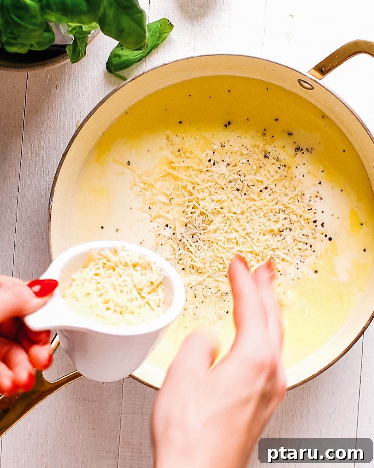 How to Make Garlic Cream Sauce 4 Adding grated parmesan to garlic cream sauce in a saucepan.